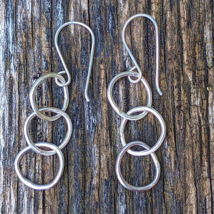 Sterling Silver Pebble Earrings lay on a rustic park bench near the Danare Designs studio.