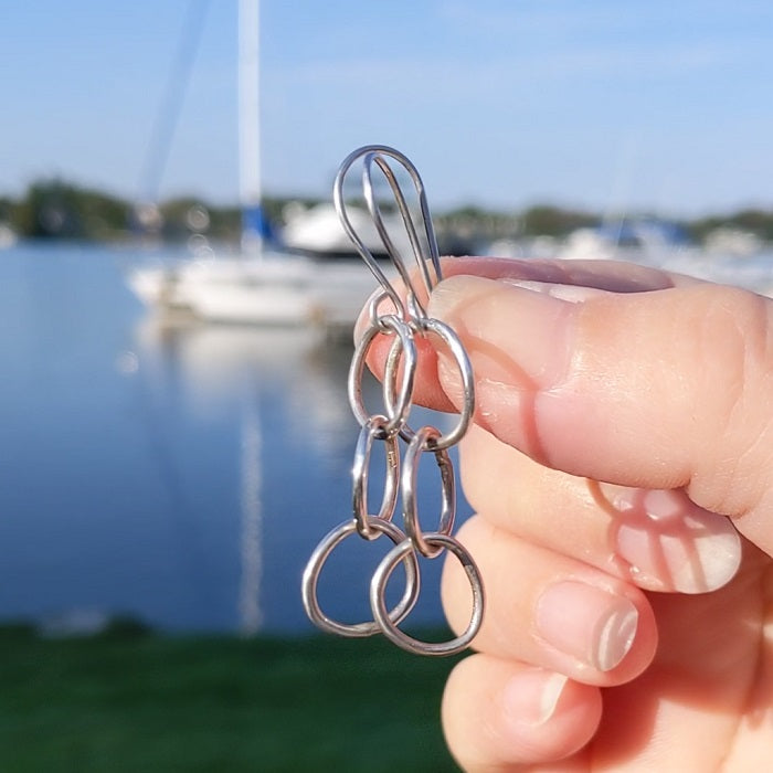 Sterling Silver Pebble Earrings shine in the sunlight  near a marina filled with sailboats.